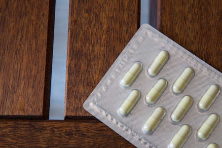 Capsule drug pack on brown wooden tableの写真素材
