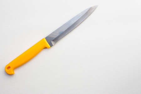 Knife with a yellow handle on white canvas backgroundの写真素材