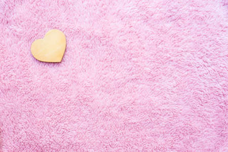 wooden heart-shaped on pink artificial woolの写真素材