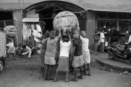 labours picking up a heavy load of goods in Koley Market, Kolkata, India.のeditorial素材
