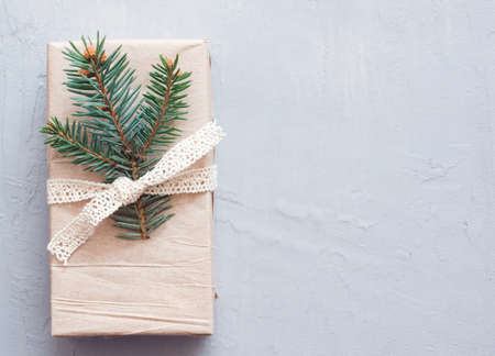 Flat lay with new years gift on a gray background. Simple paper packaging, fir twigs. Banner on a Christmas theme, space for textの写真素材