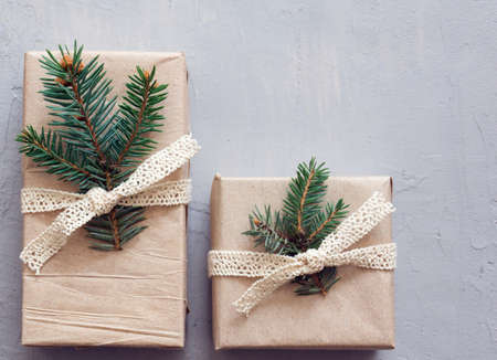 Flat lay with two new years gifts on a gray background. Simple paper packaging, spruce twigs. Banner...