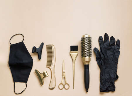 Hairdressing tools on a beige background. Hair salon accessories, scissors, clips, combs, gloves and face mask.の写真素材