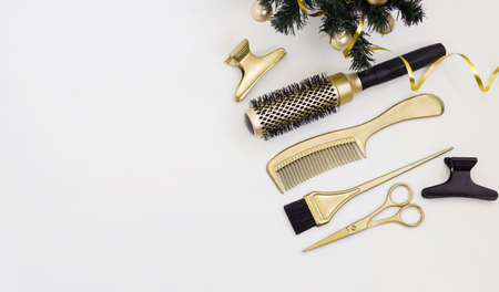Banner with hairdressing tools in gold color and a Christmas tree on a white background. Holiday template with hair salon accessories with space for text.の写真素材