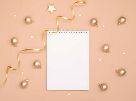 Christmas and new year card, or mock up on a pink peach background. Empty blank Notepad and small Golden balls, space for text.の写真素材