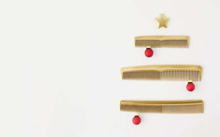 Christmas tree made of combs on a white background. New years banner for hair salon. Template for a Barber greeting card. Holiday picture with gold accessories.の写真素材