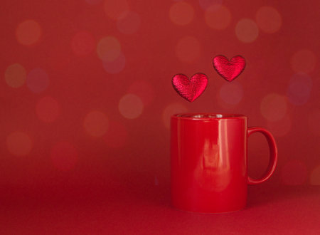 Valentines day banner with a red mug and two hearts on a bokeh background. Greeting card or template for a holiday design.の写真素材