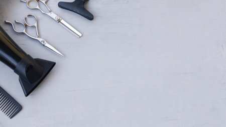 Hairdressing tools in the corner on a light gray background with space for text. Hair salon accessories, scissors, hair dryer and comb.の写真素材