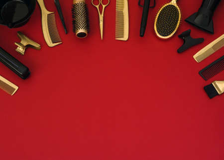 Background with hairdressing tools on red. Hair salon accessories black and gold, hair dryer, combs,...