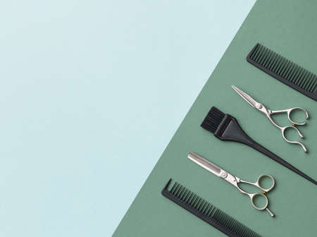 Hairdressing tools on a green background and a blue sheet with space for text. Black and steel hair...