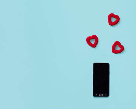 Phone and red hearts on a blue background. The concept of online dating, correspondence. Template with space for textの写真素材