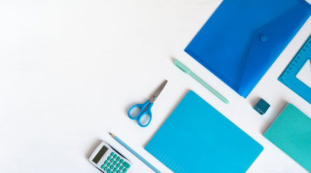 Blue green stationery in the corner and copy space. Accessories for writing and counting on a white table, a notebook, a ruler, scissors, a pencil, a penの写真素材