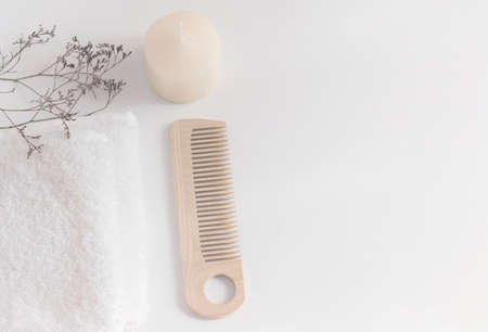 A towel, a candle, a comb and dried wildflowers on a white table