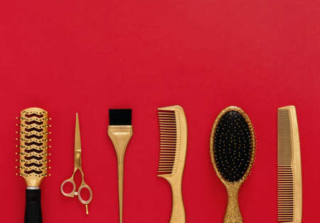 Background with hairdressing tools on red. Hair salon accessories gold, hair combs, scissors. Banner and template for design with space for textの写真素材