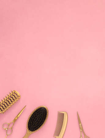 Golden hairdressing tools on a pink background. Vertical template with hairdressing accessories and space for textの写真素材