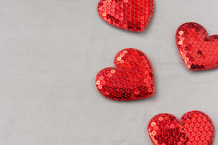 Shiny red hearts with sequins on a gray textured background. Template for design and text for...