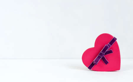 A small heart shaped box with ribbon. Gift on white background. Template with copy space for Valentines Day greetings.の写真素材