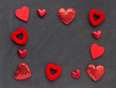 Shiny red hearts with sequins and different shapes on a dark black background. Template for design...