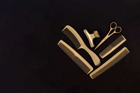 Hairdressing tools in black and gold on concrete background. Hair salon accessories, combs, scissors and hair clips with copy space. Template for business cardsの写真素材