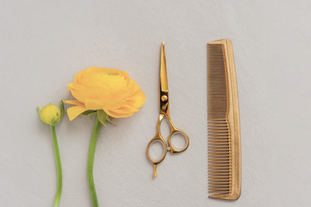 Barber scissors comb yellow flower on gray background. Gold colored hair salon accessories.の写真素材