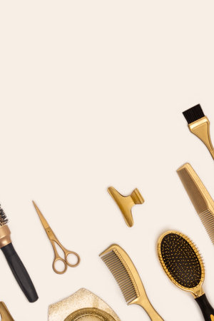 Golden hairdressing tools on beige background. Vertical template with hairdressing accessories and space for textの写真素材