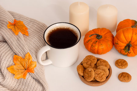 Morning coffee, autumn atmosphere. Mug, scarf, cookies, pumpkins and candles on tableの写真素材