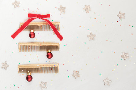 Golden hairdressing tools in the shape of Christmas tree on gray. Ð¡omb with bow, balls, flatlay, top view. Wintertime holidays card, template.の写真素材