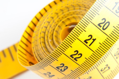 Roll of yellow measuring tape rolled up over white backgroundの写真素材