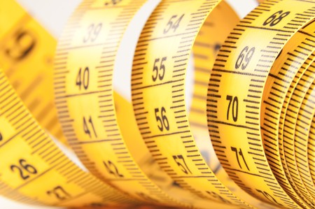 Roll of yellow measuring tape rolled up over white background