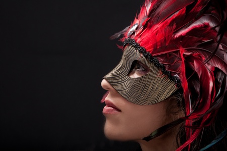 Beautiful model wearing a feather mask symbolizing mardi gras or venetian carnivalの写真素材