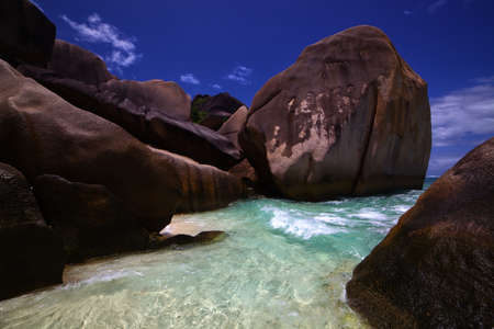 Clear ocean water washes in among weathered shore rocks worn smooth from years of wavesの写真素材