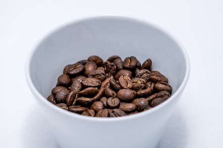 Coffee beans isolated on a white background in a white cupの写真素材