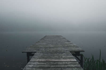 Footbridge in the autumn on a lake with much fog in the bavarian forestの写真素材