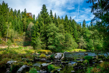 River with stones and moss in the autumn and a rock in front of and clouds on the sky in the bavarian forestの写真素材