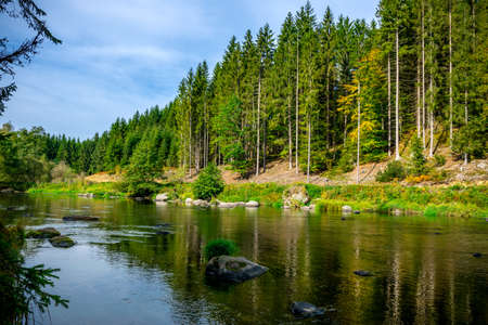 River with stones and moss in the autumn and a rock in front of and clouds on the sky in the bavarian forestの写真素材