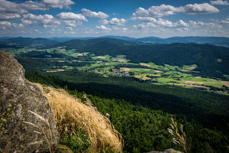 View from top of a mountain with rocks and stones and much clouds on the sky on a sunny day in the bavarian forestの写真素材