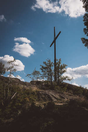 Summit Cross on the top of a mountain with clouds in the sky in the bavarian forestの写真素材