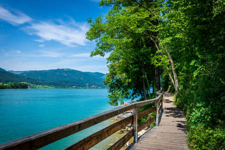 Jetty on the edge of the turquoise lake called Wolfgangsee mountains in the background and clouds on the skyの写真素材