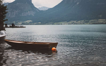 Wooden boat on the pier in a sea in austria with mountains in the backgroundの写真素材