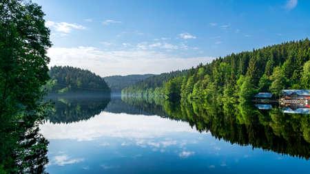Reflection from the sky in the water in the lake with trees in the bavarian forestの写真素材