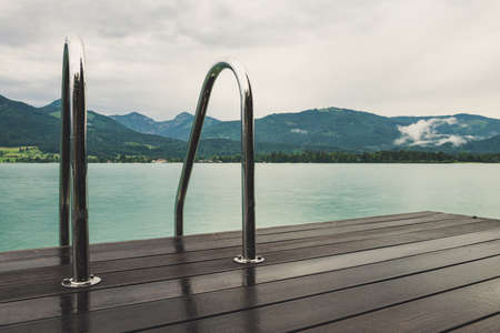 footbridge with a pool ladder in the lake in Austria which wolfgangsee is called with mountains in the backgroundの写真素材