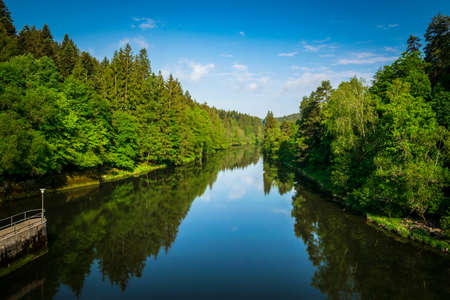 River with reflection from trees and clouds on the sky in the bavarian forestの写真素材