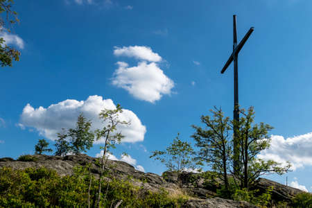 Summit Cross on the top of a mountain with clouds in the sky in the bavarian forestの写真素材