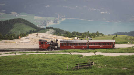 Rack Railway in austria on top of a mountain with a bench in front of and a sea in the background in the valleyの写真素材