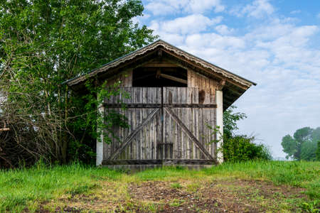Old Barn with clouds and grass in the bavarian forest and a field in front ofの写真素材