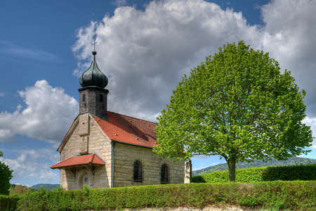 Small Chapel with clouds on the sky and tree in the bavarian forestの写真素材
