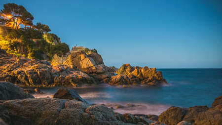 Ocean at the night with rocks in front of the water in lloret de marの写真素材