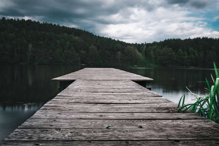 Footbridge on a lake with clouds on the sky in the bavarian forestの写真素材