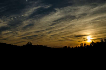 Clouds on the sky with sunset and trees in front of in the bavarian forestの写真素材