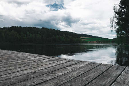Footbridge on a lake with clouds on the sky in the bavarian forest